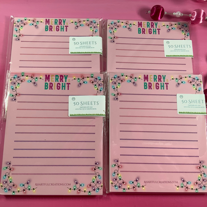 Set of four pink notepads with 'Merry Bright' text on a pink background