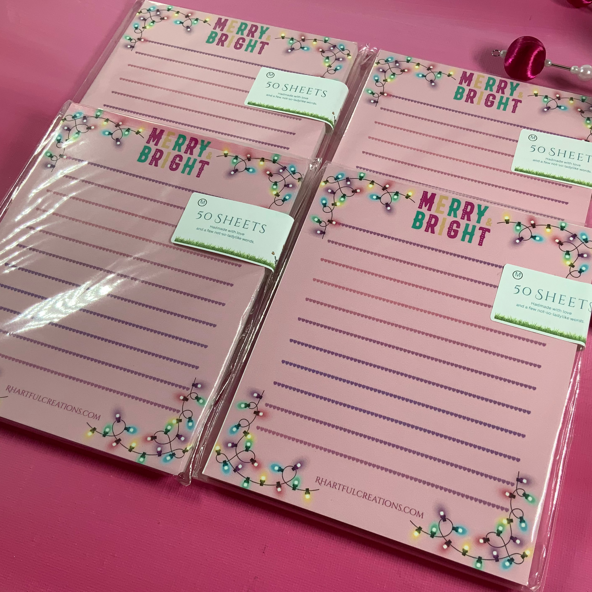 Set of pink notepads with 'Merry Bright' text on a pink background