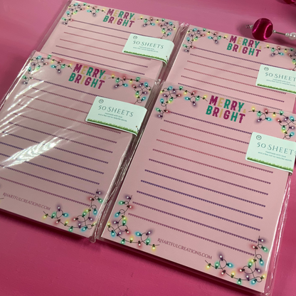 Set of pink notepads with 'Merry Bright' text on a pink background