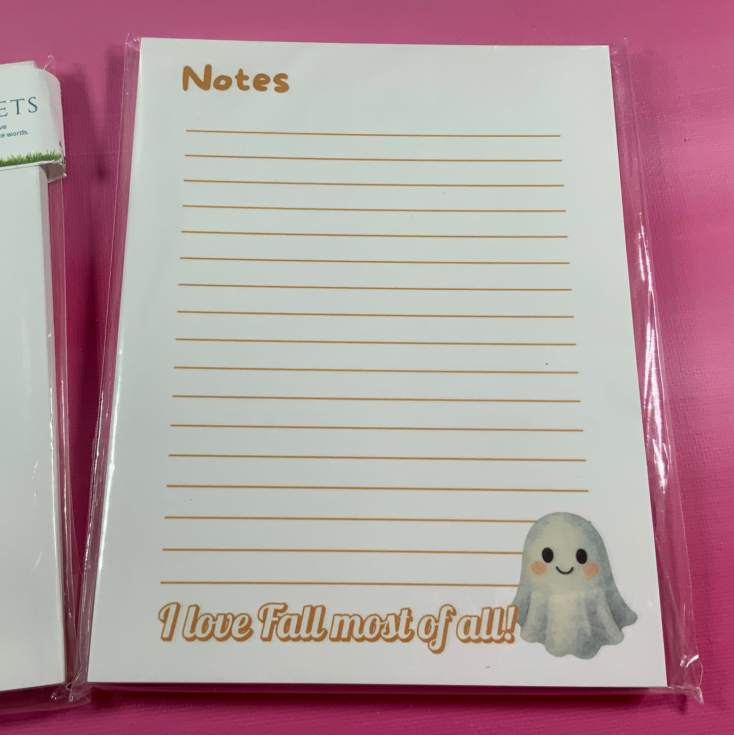 Notepad with lined pages and a ghost illustration on a pink background