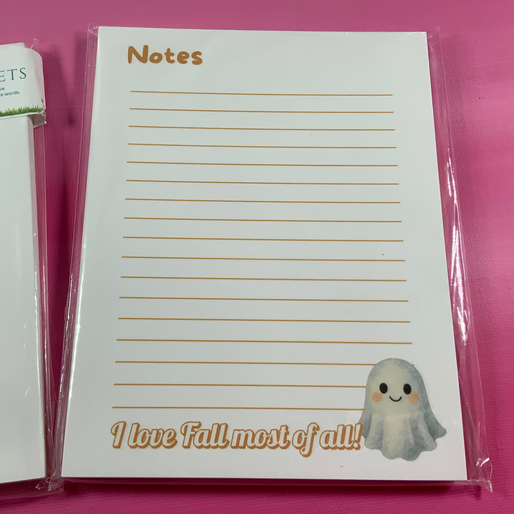 Notepad with lined pages and a ghost illustration on a pink background