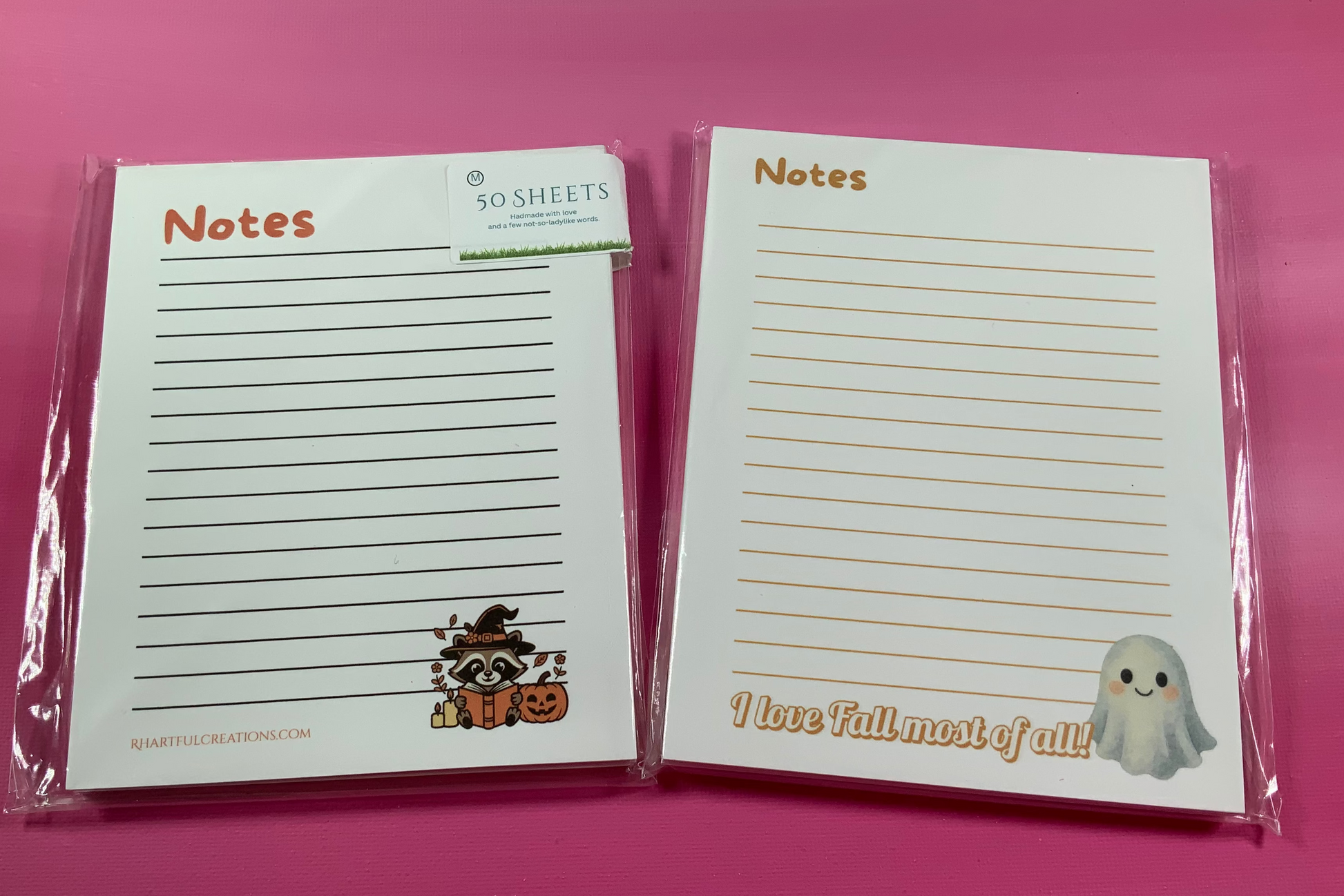 Two Halloween-themed notepads with cute illustrations on a pink background