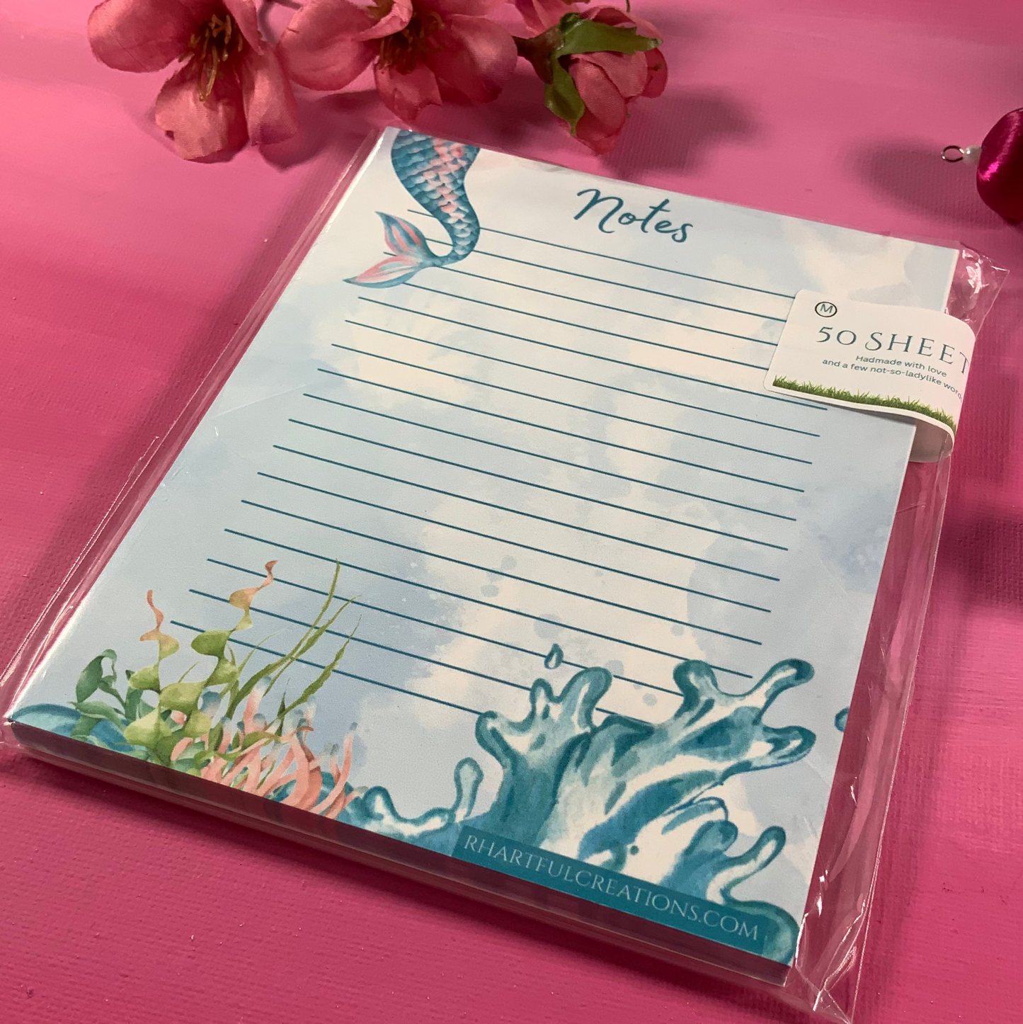 Notepad with ocean-themed design on a pink background