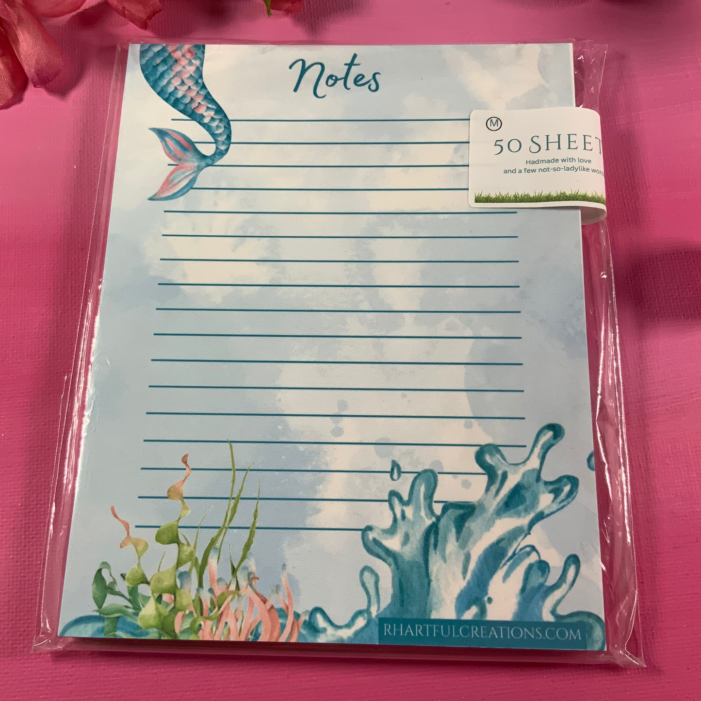 Notepad with mermaid design on a pink background