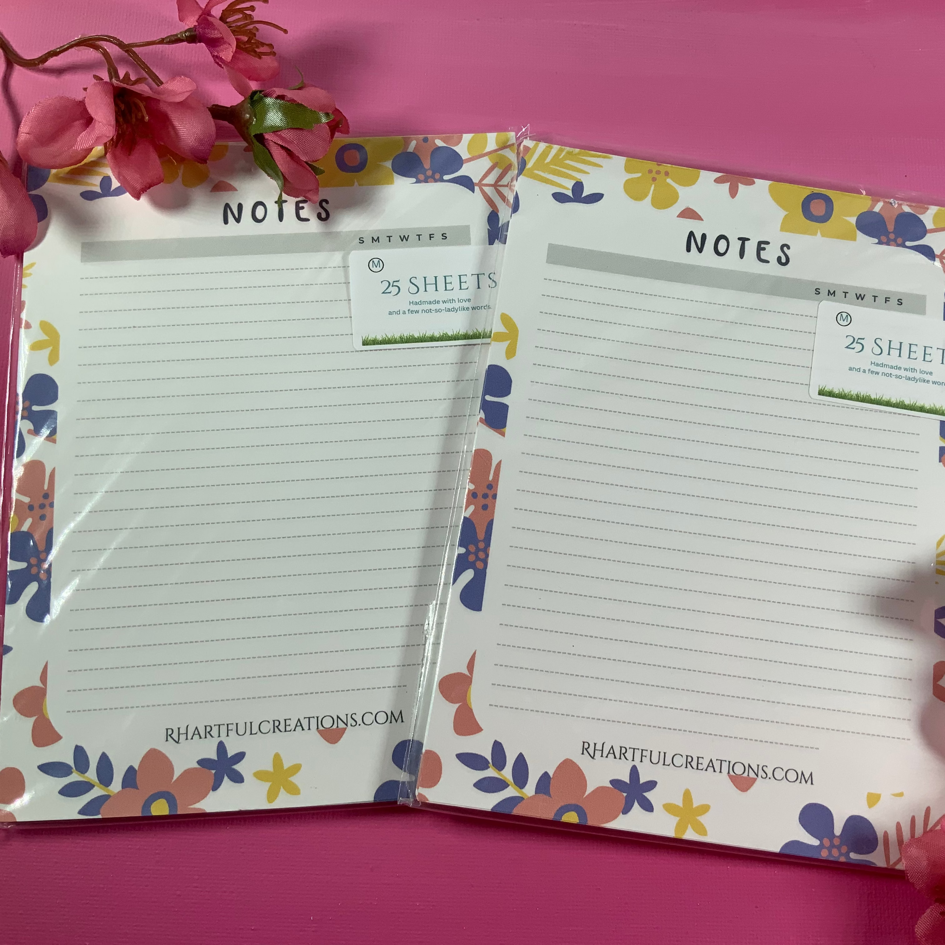 Two floral-themed notepads with pink flowers on a pink background