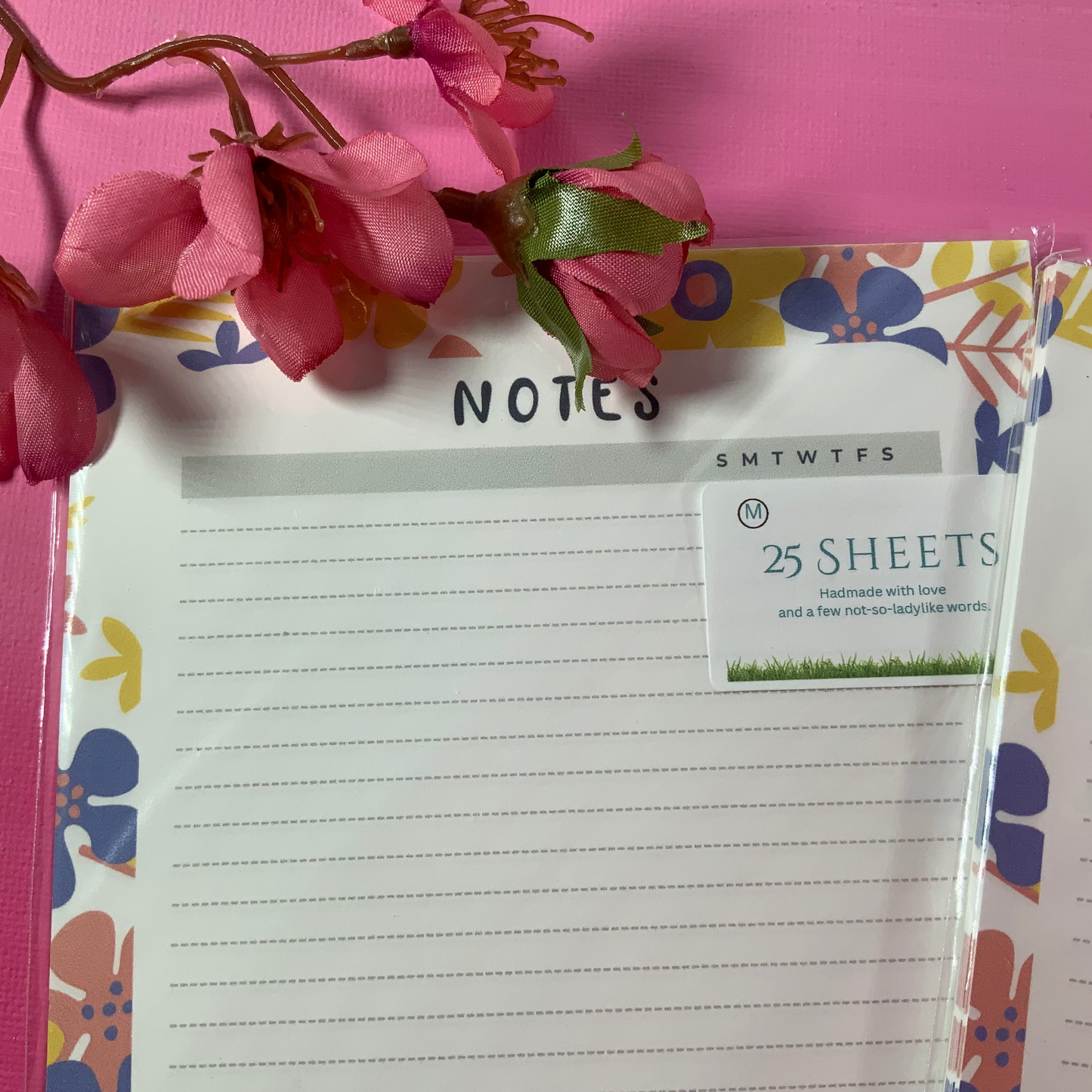 Notepad with floral design on a pink background with flowers