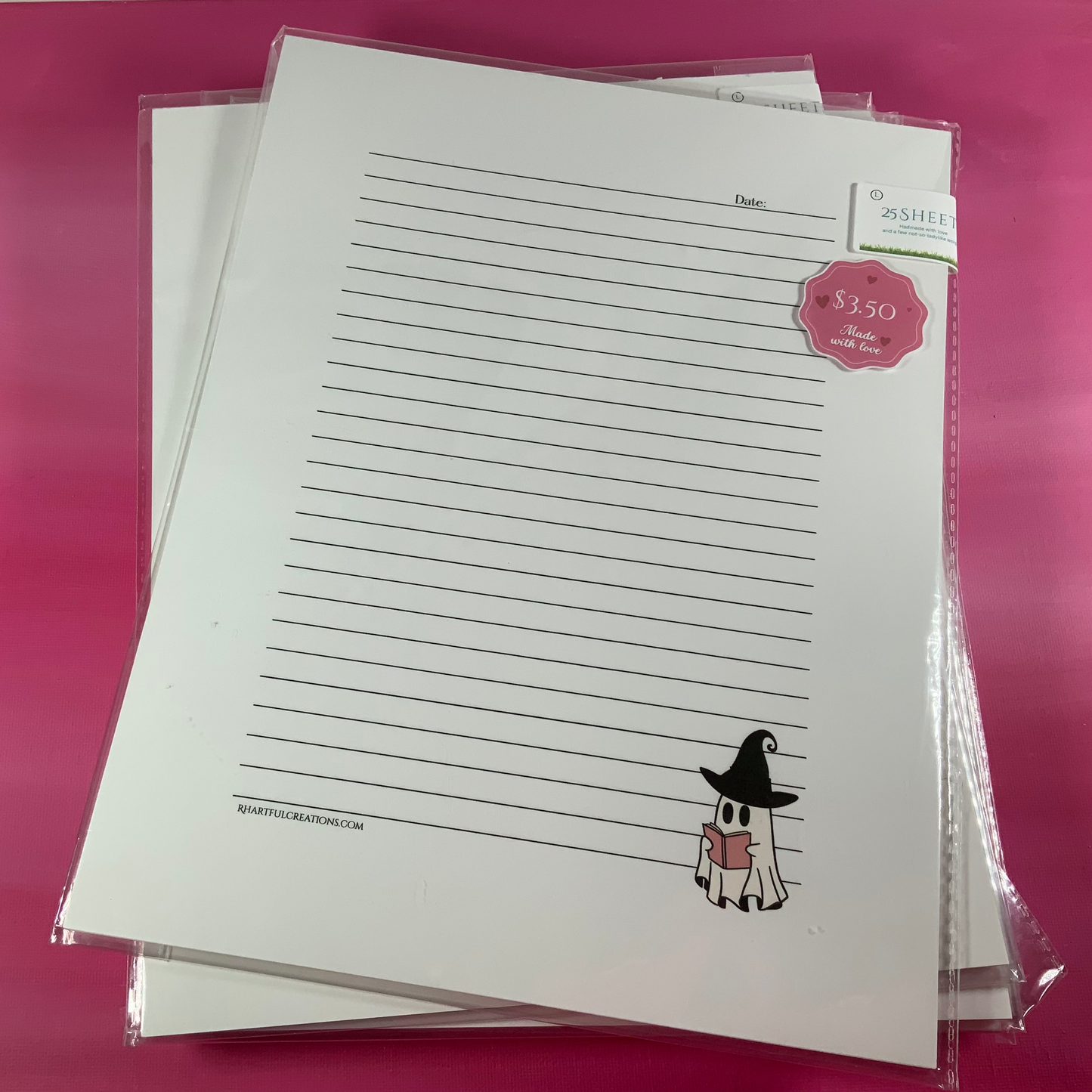 Stack of lined paper with a cartoon ghost design on a pink surface