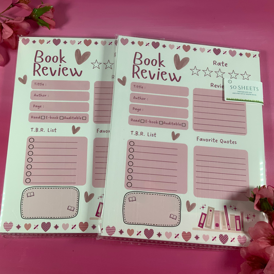 Two open notebooks with book review pages on a pink background with flowers.