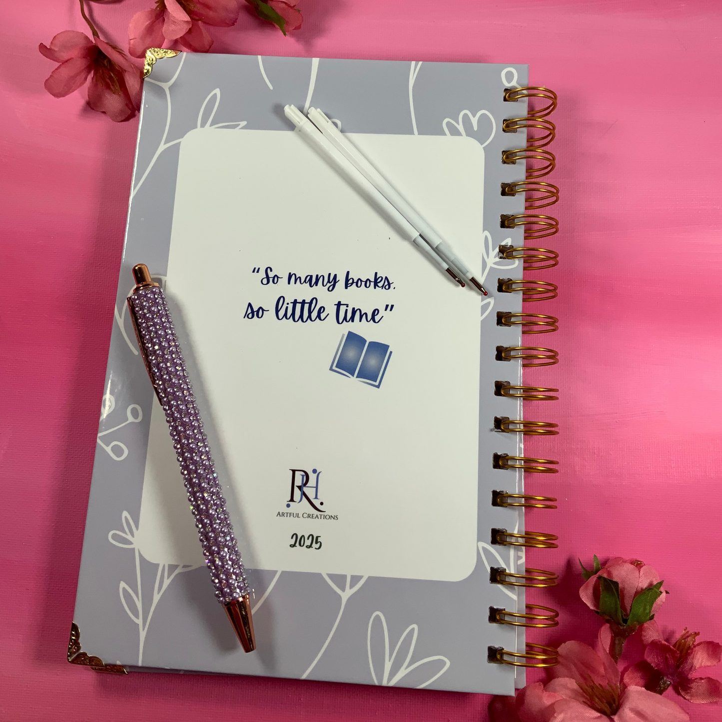 Notebook with pen on a pink background with flowers