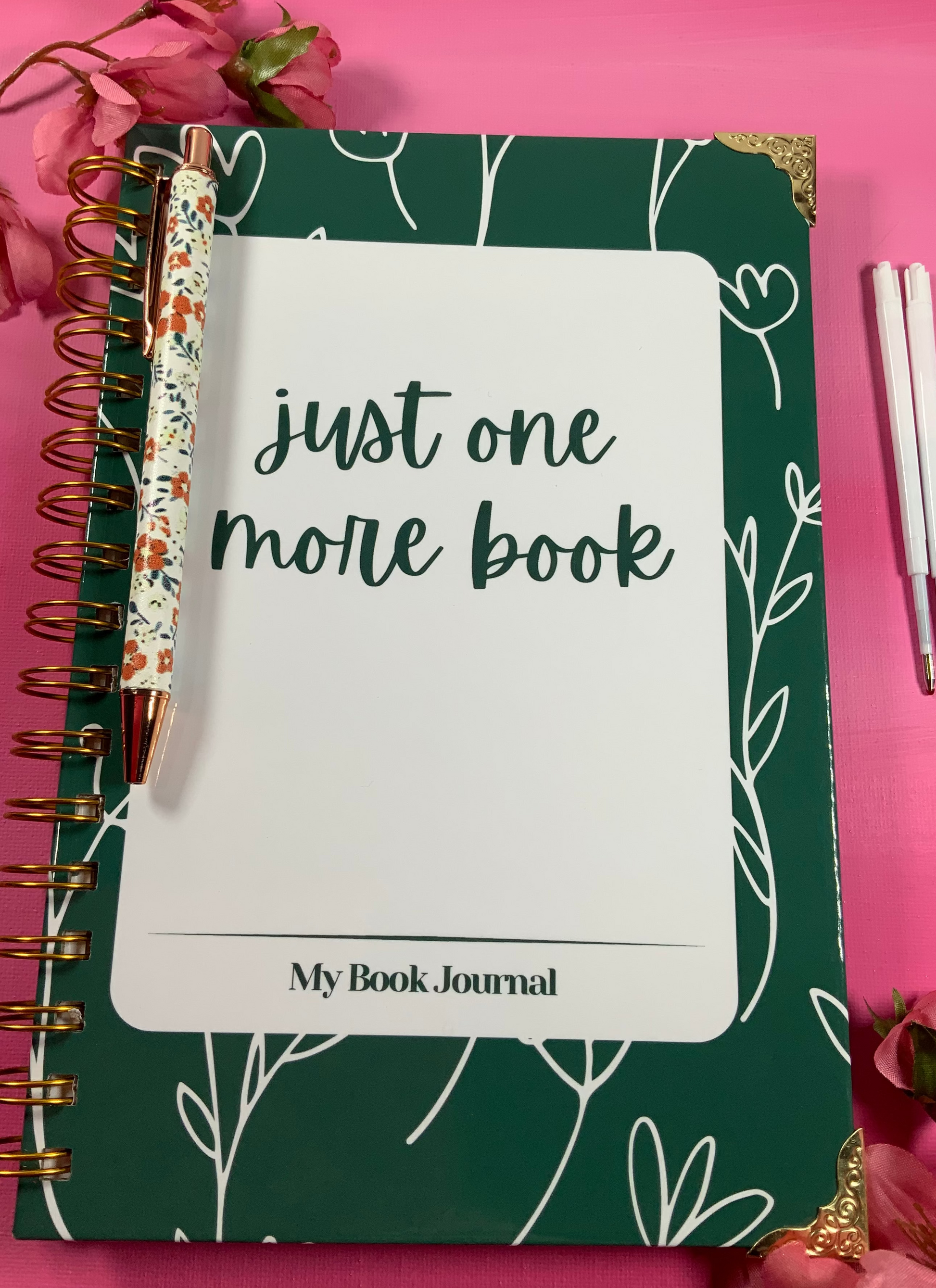 Green notebook with 'just one more book' text on a pink background