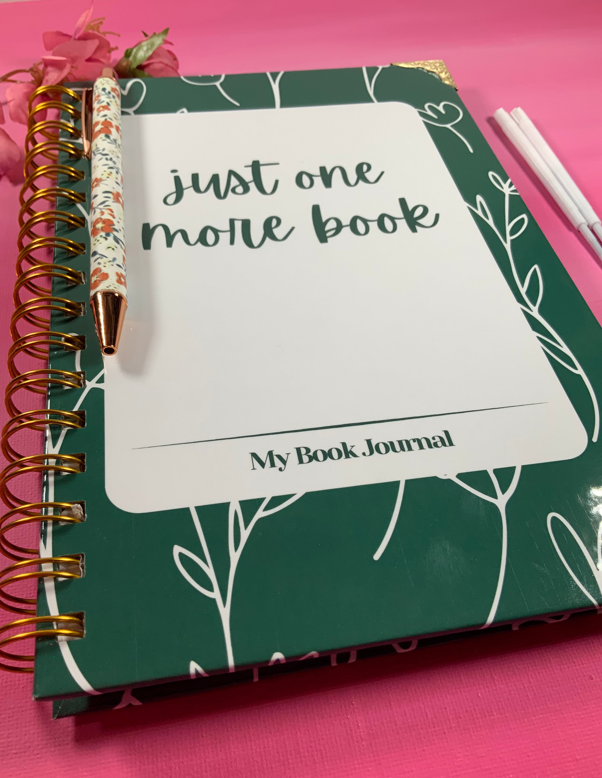 Book journal with 'Just one more book' text on a pink background