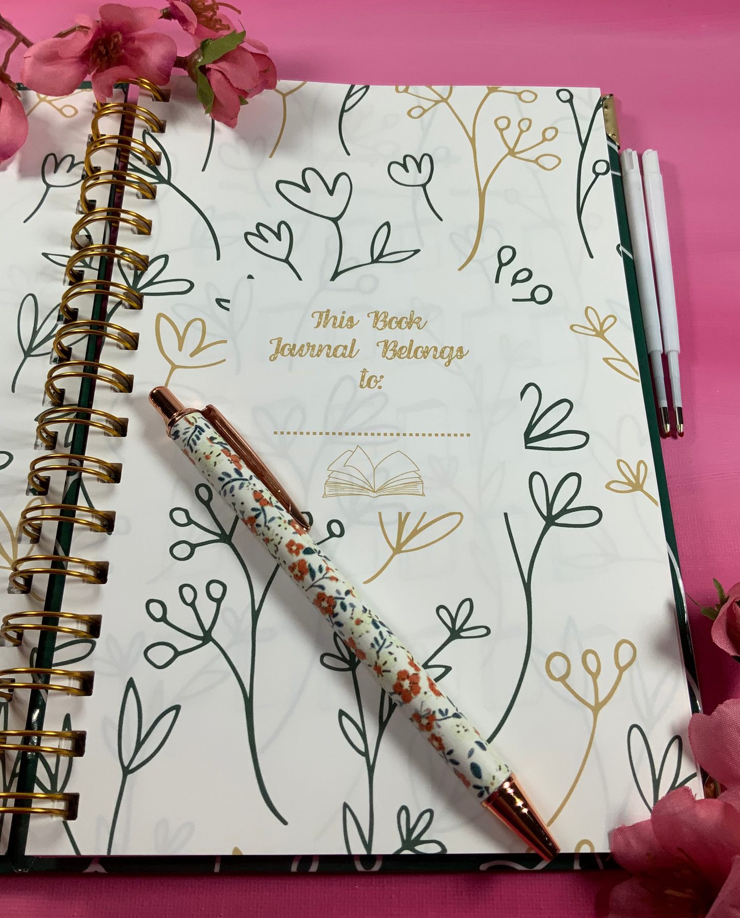 Notebook with floral design and pen on a pink background
