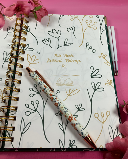 Notebook with floral design and pen on a pink background