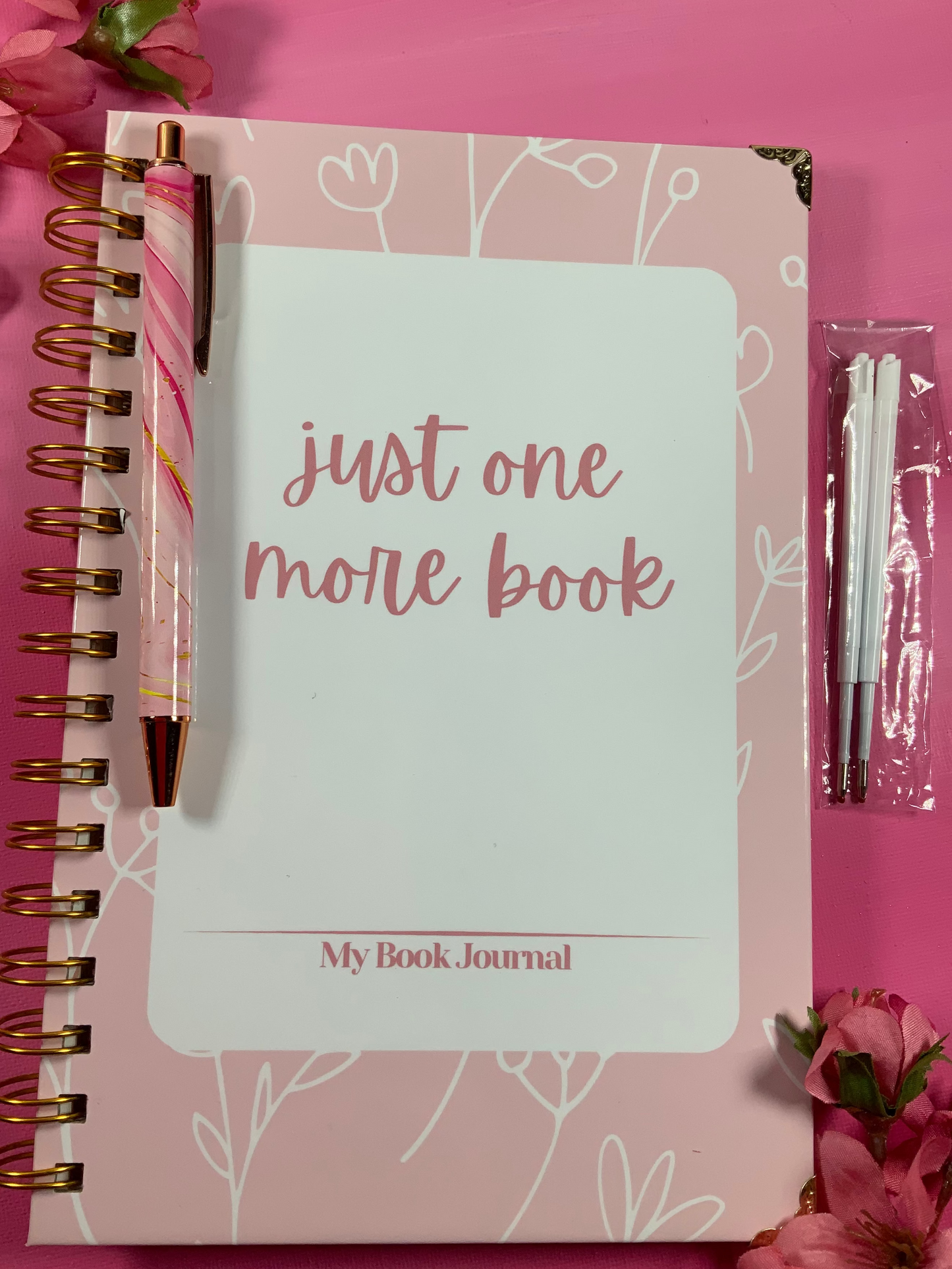 Pink notebook with floral design and text on a pink background