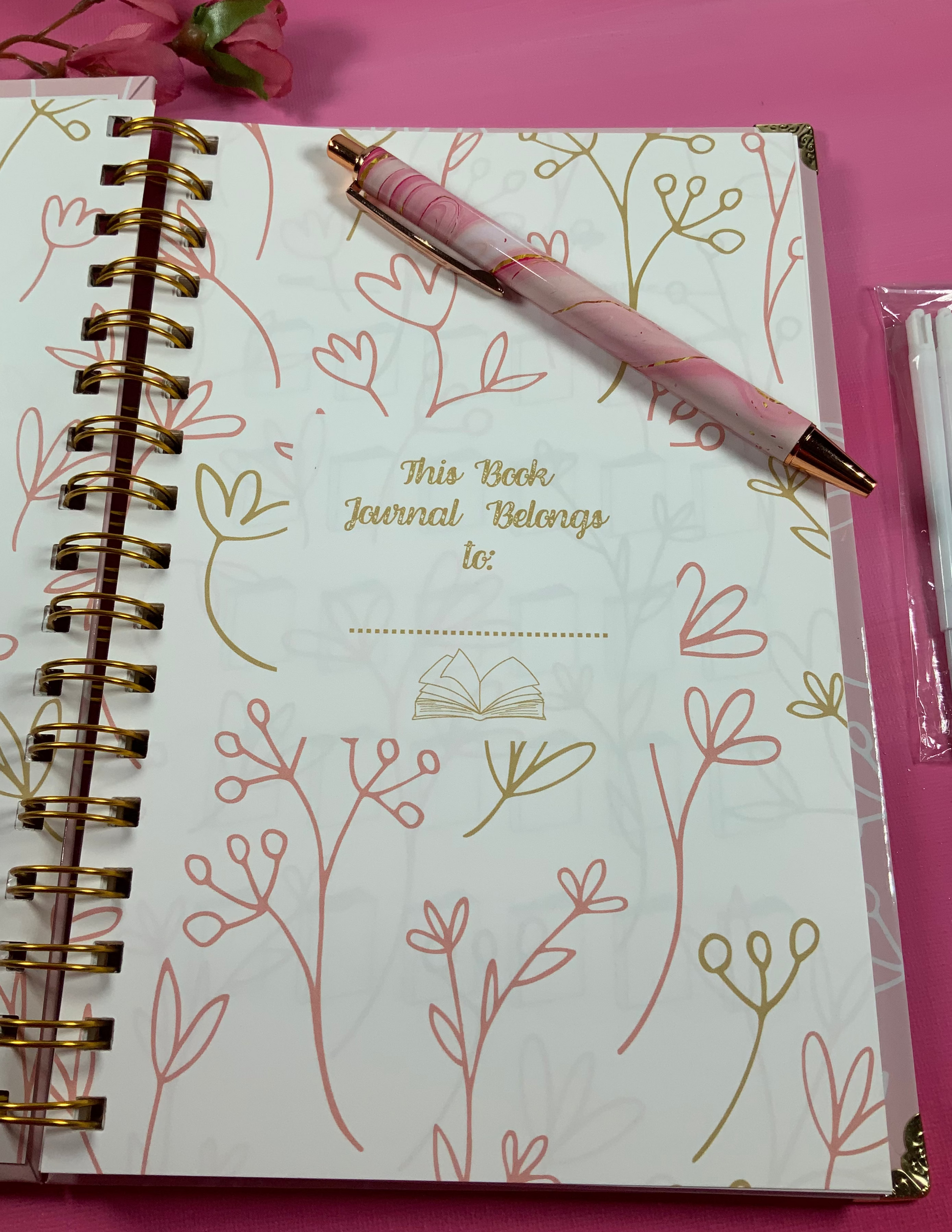 Notebook with floral design and pen on a pink background