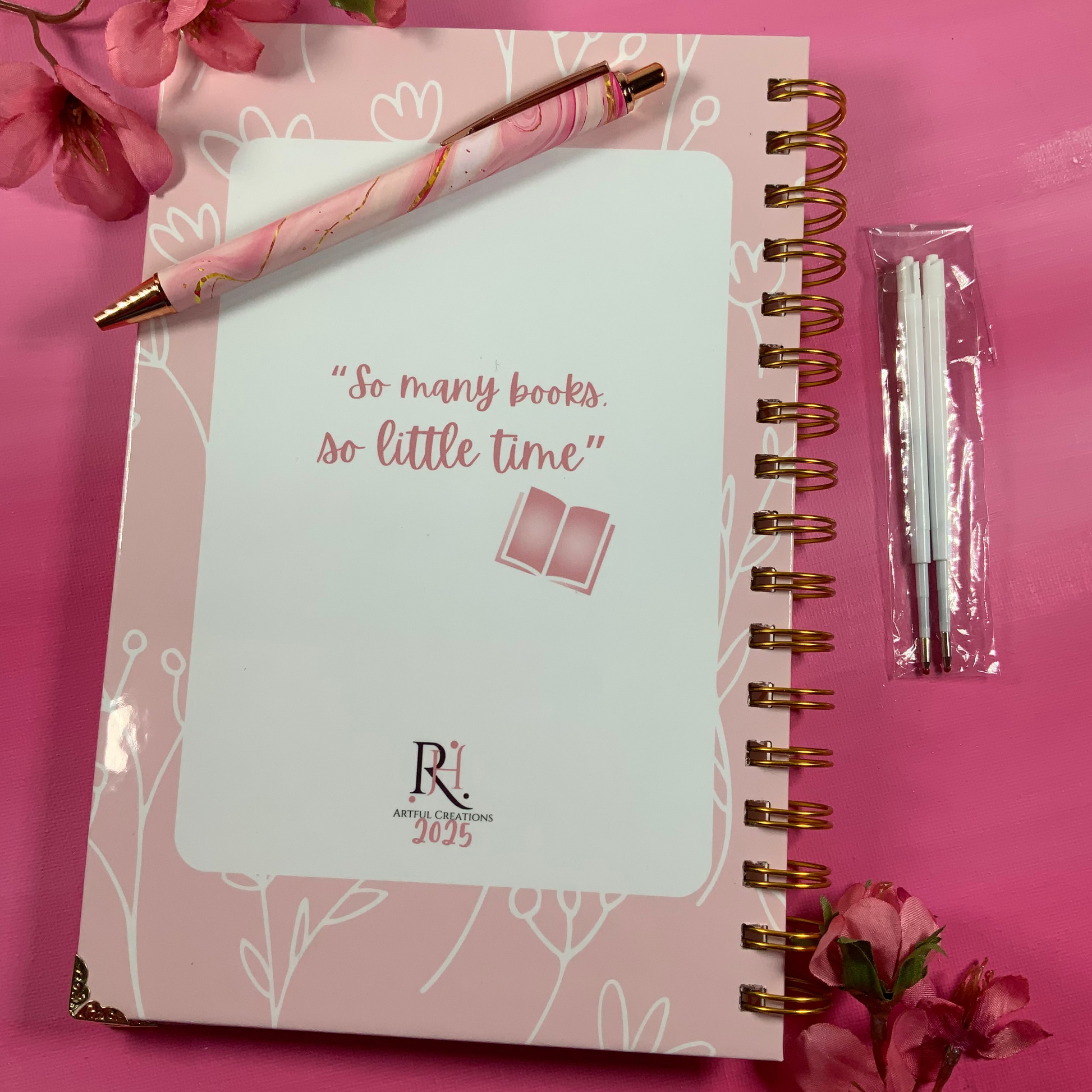 Notebook with pen and flowers on a pink background