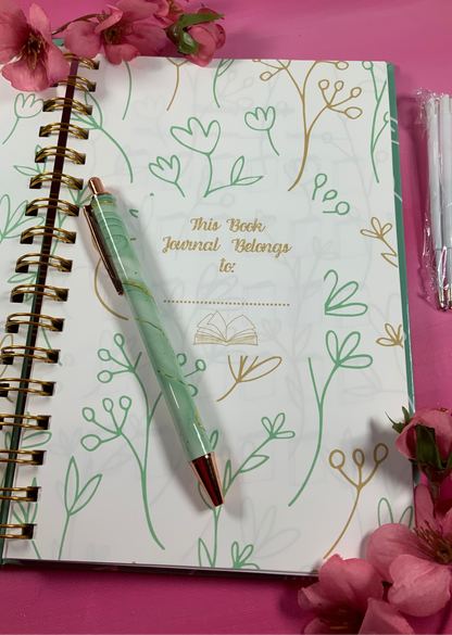 Journal with floral design and pen on a pink background