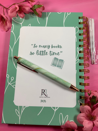 Green notebook with a pen and cherry blossoms on a pink background