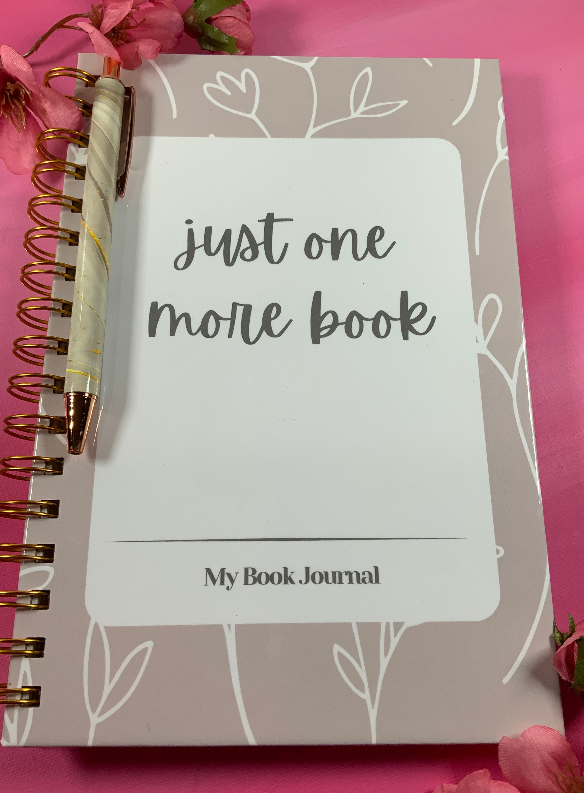 Notebook titled 'Just One More Book' with floral design on pink background