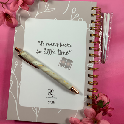 Notebook with pen and flowers on a pink background