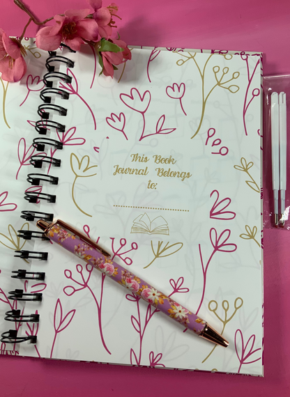 Journal with floral design and pen on a pink background