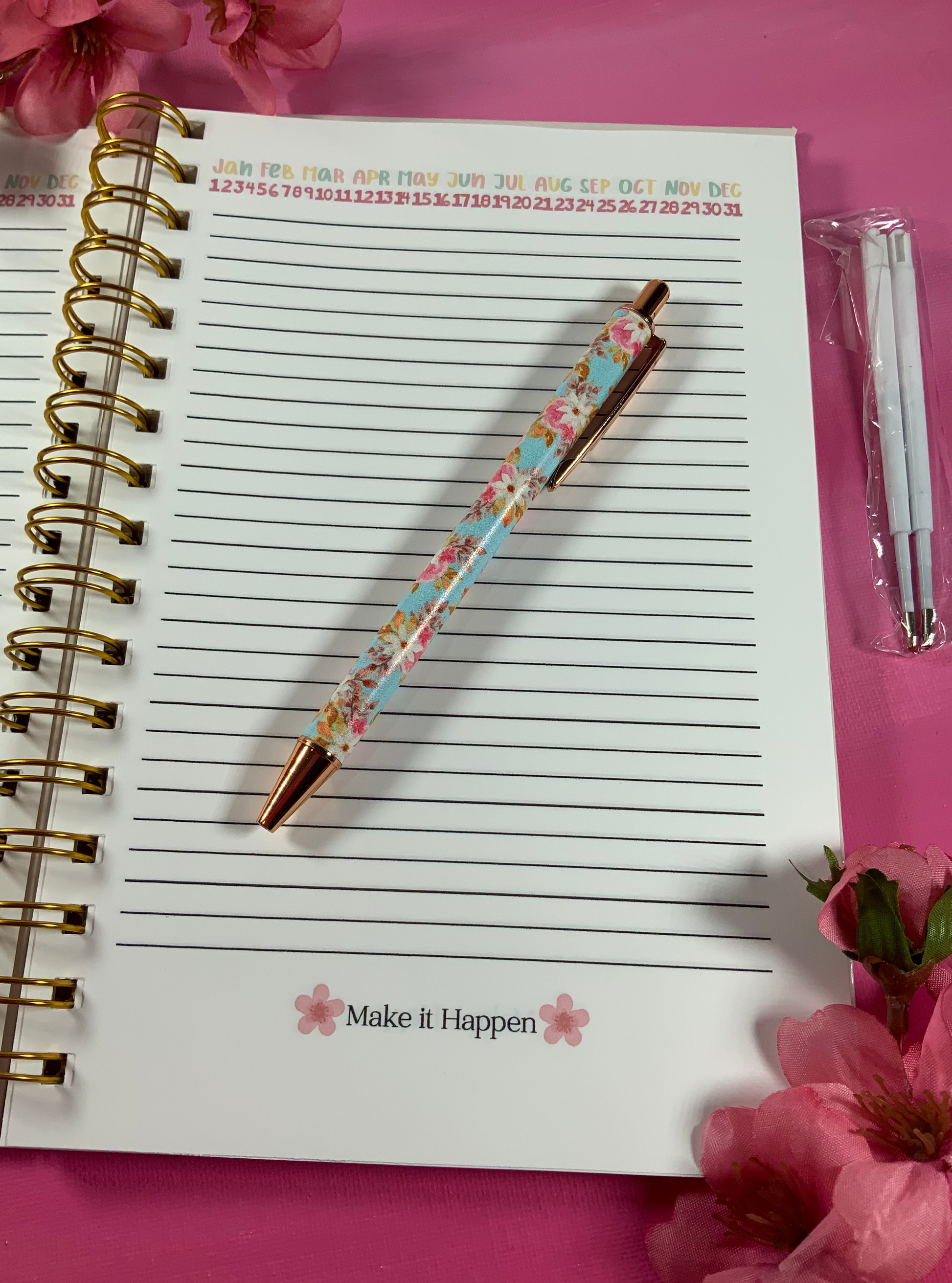 Notebook with a floral pen on a pink background