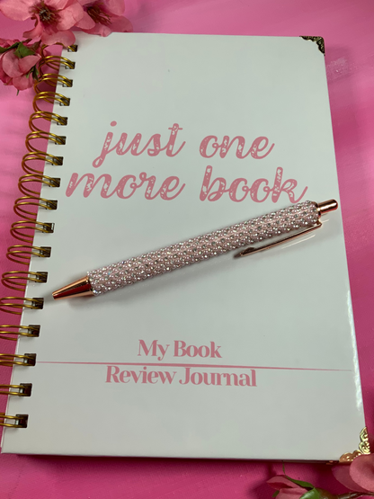 Book review journal with a pen on a pink background