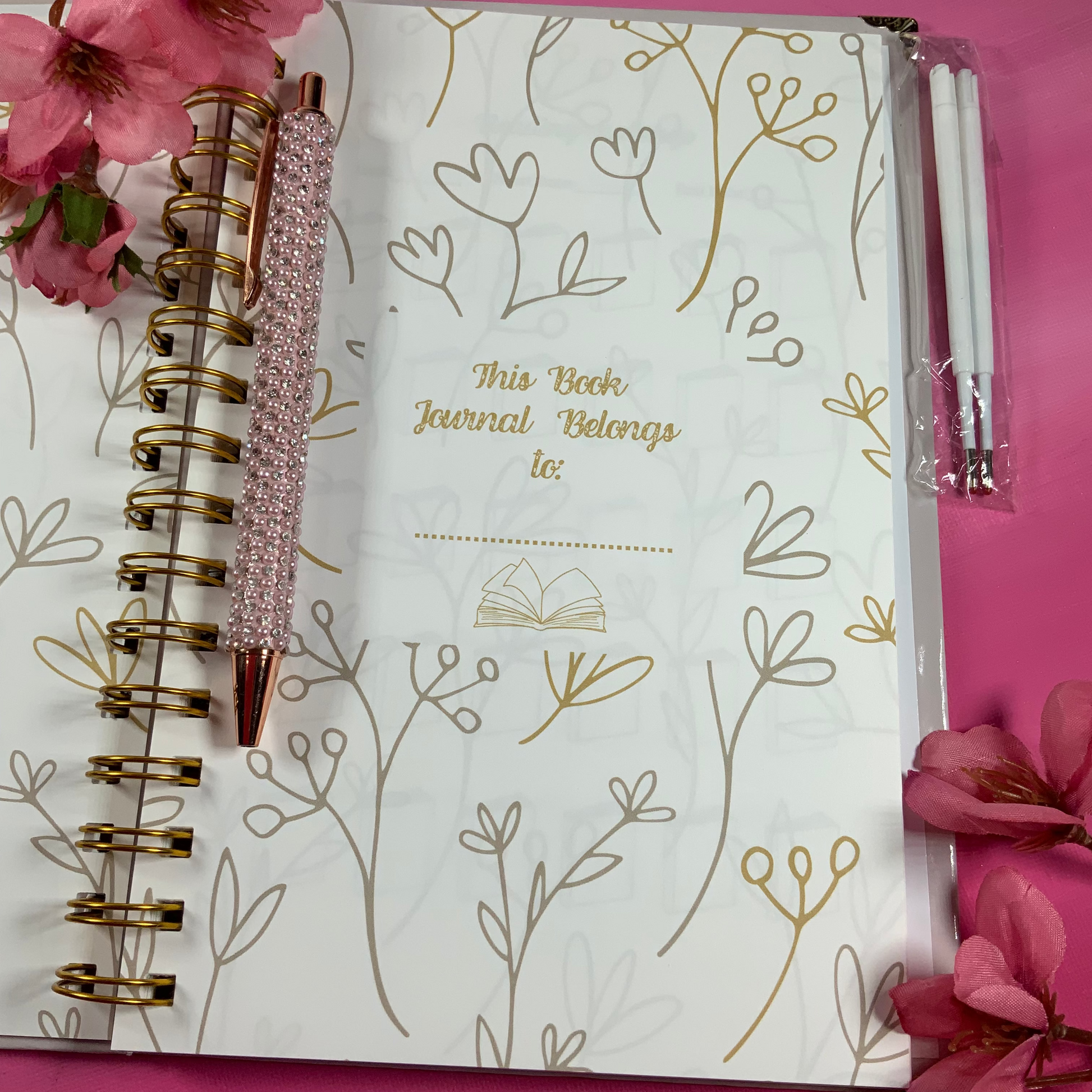 Journal with floral design and pen on a pink background