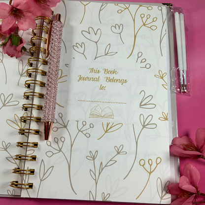Journal with floral design and pen on a pink background