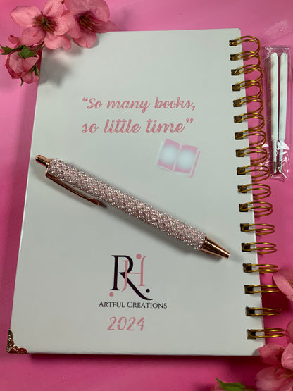 Spiral-bound notebook with a decorative pen on a pink background