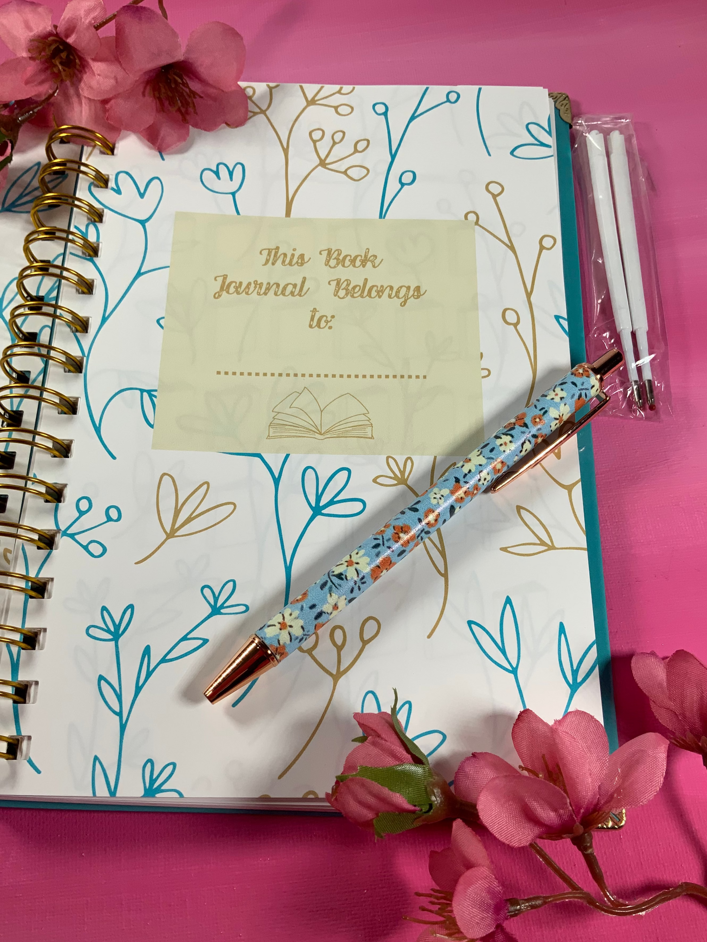 Journal with floral pen and pink flowers on a pink background