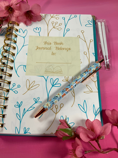 Journal with floral pen and pink flowers on a pink background