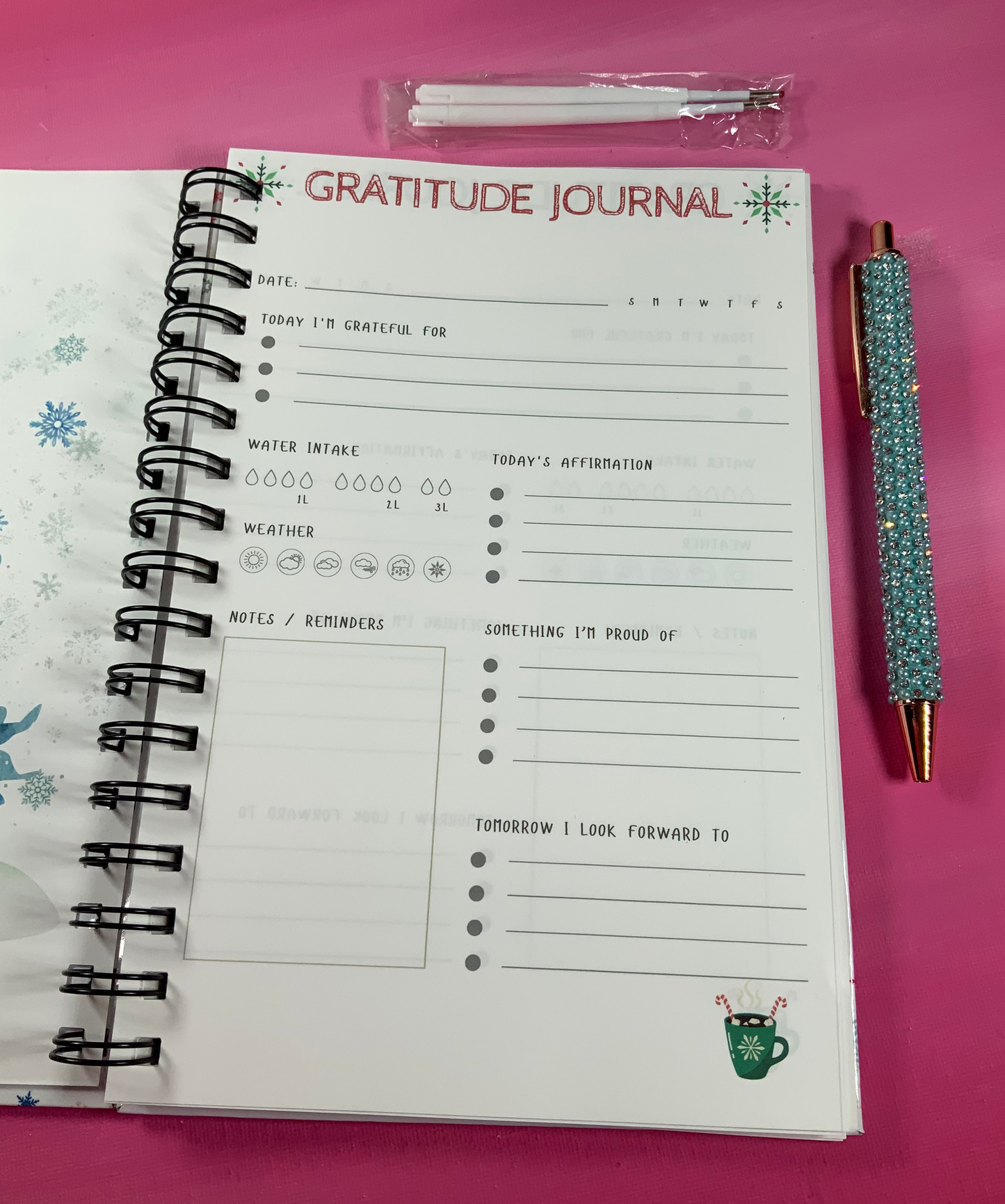 Gratitude journal with pen on a pink background