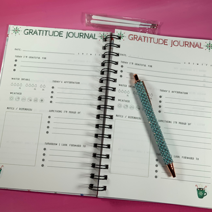 Gratitude journal with a pen on a pink surface