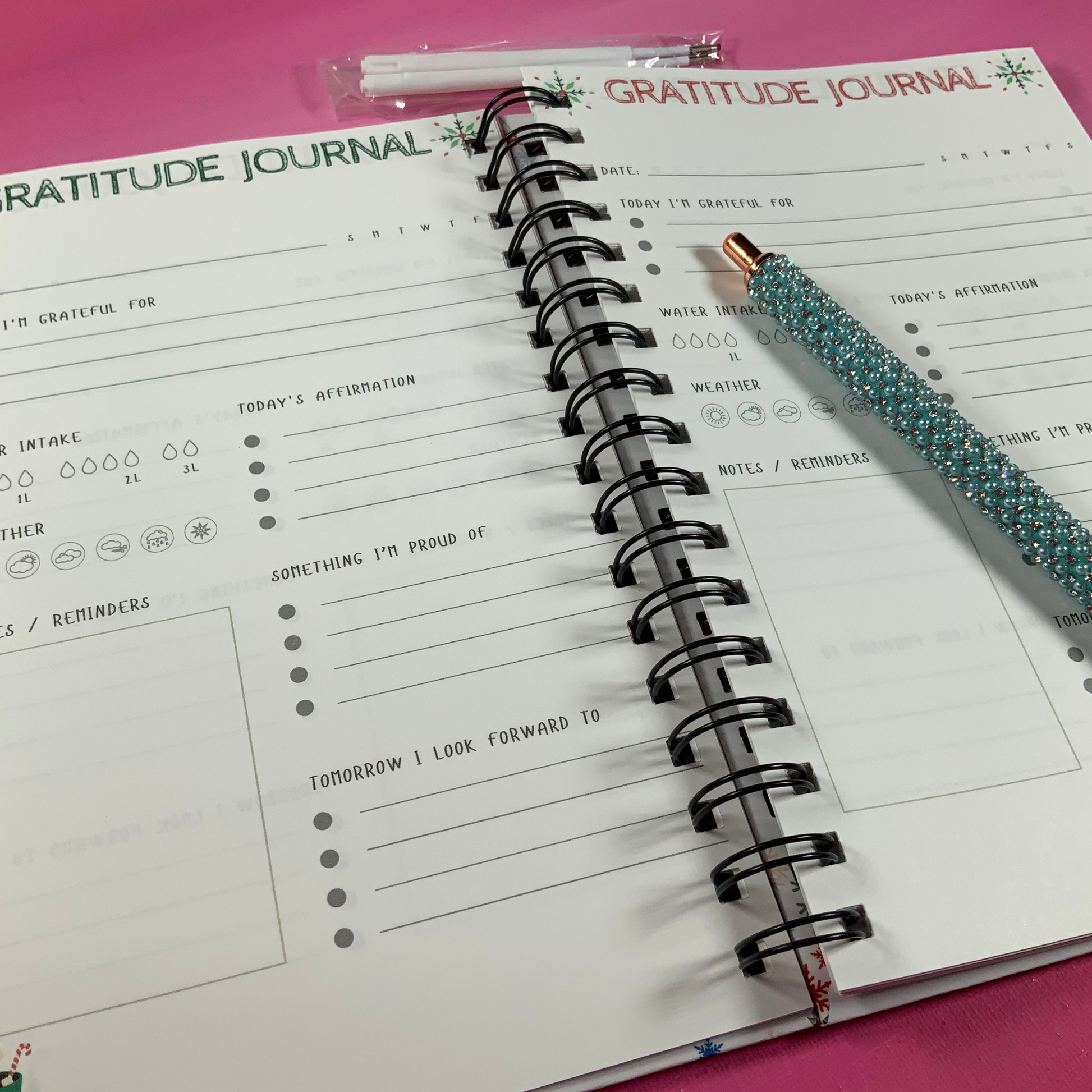 Gratitude journal with a pen on a pink surface