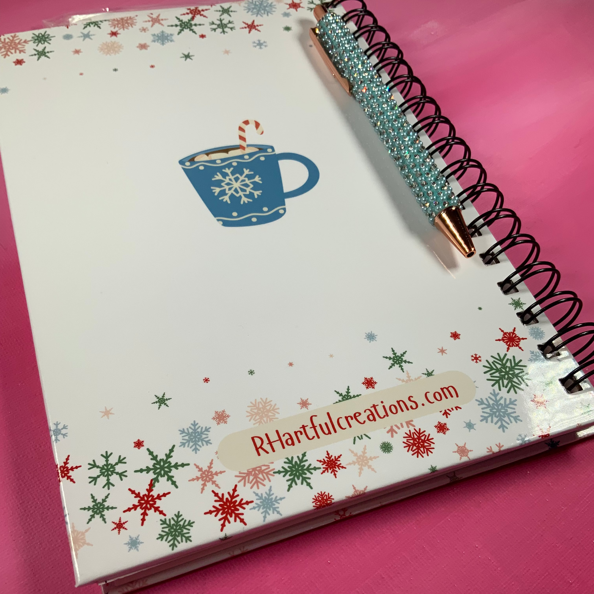 Notebook with snowflake design and pen on a pink background