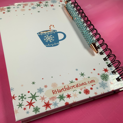 Notebook with snowflake design and pen on a pink background