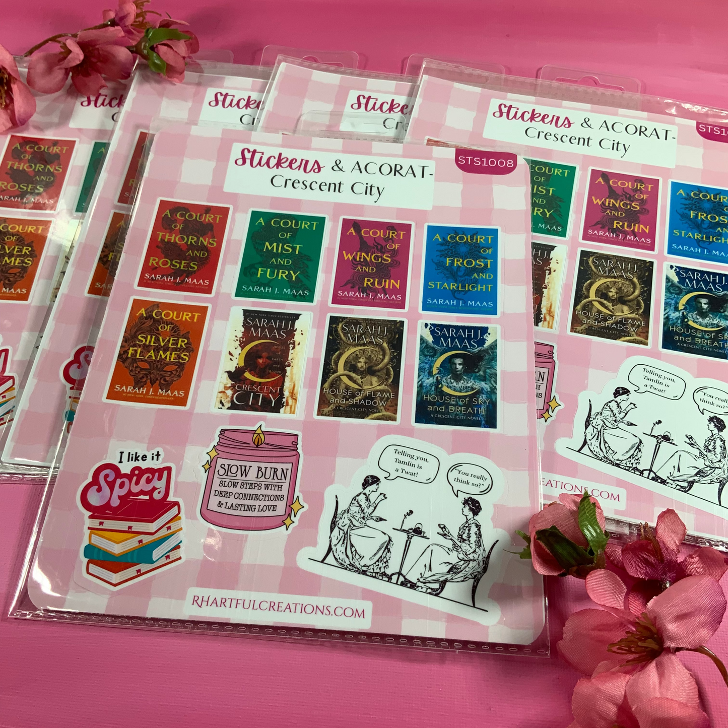 Sticker sheets with book-themed designs on a pink surface with flowers.