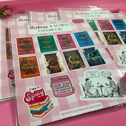 Sticker sheets with book-themed designs on a pink surface