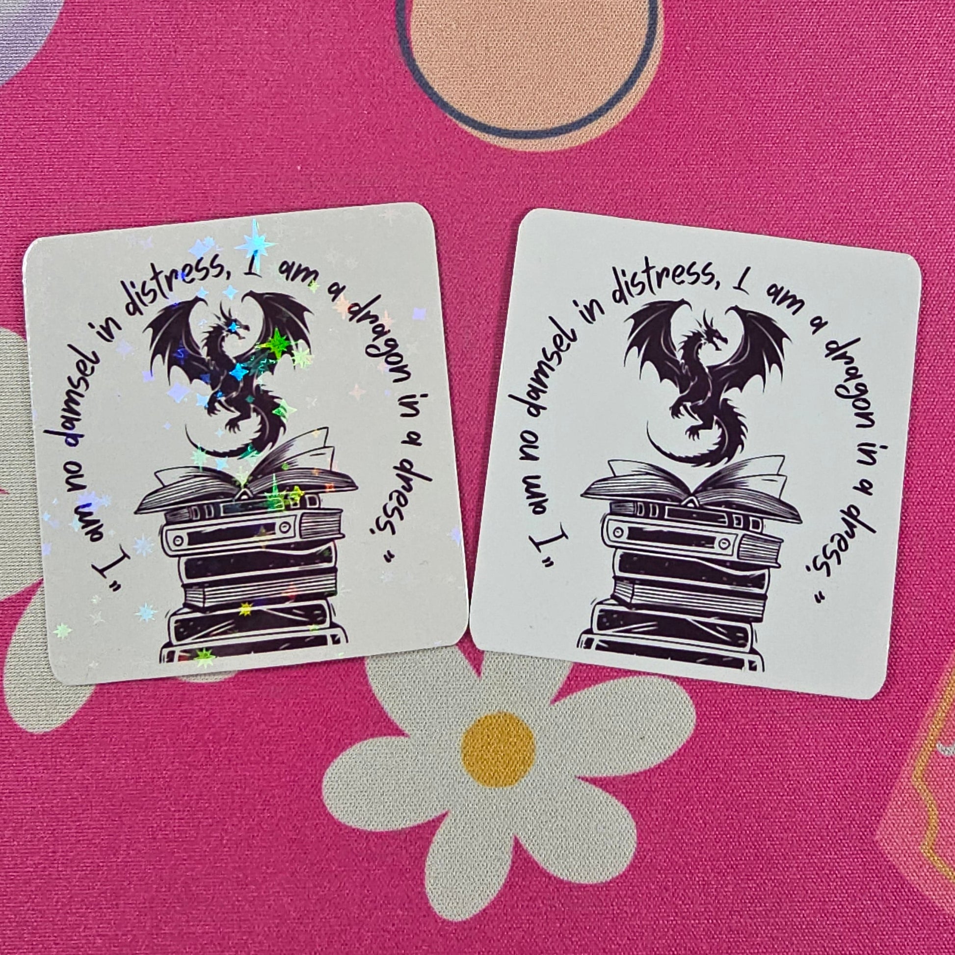 “I am no damsel in distress, I am a dragon in a dress” sticker featuring a black dragon sitting atop stacked books, handmade by RH Artful Creations.