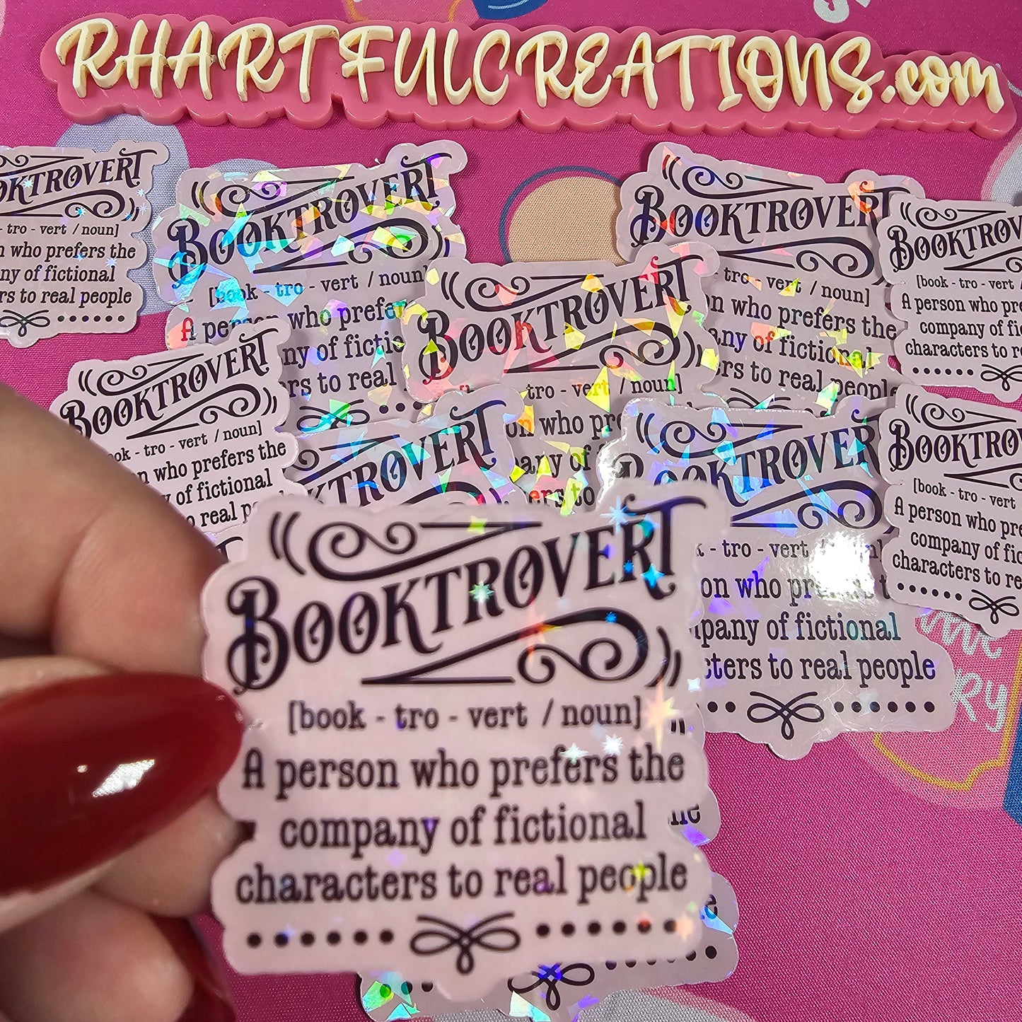 Sticker with 'Booktrover' definition held by a hand against a pink background with text and book illustrations.