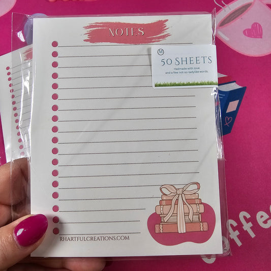 Notebook with decorative design held by a hand against a pink background