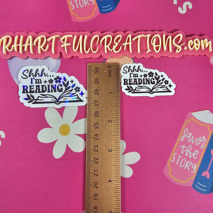 Stickers with text and a ruler on a pink background with book and flower designs.
