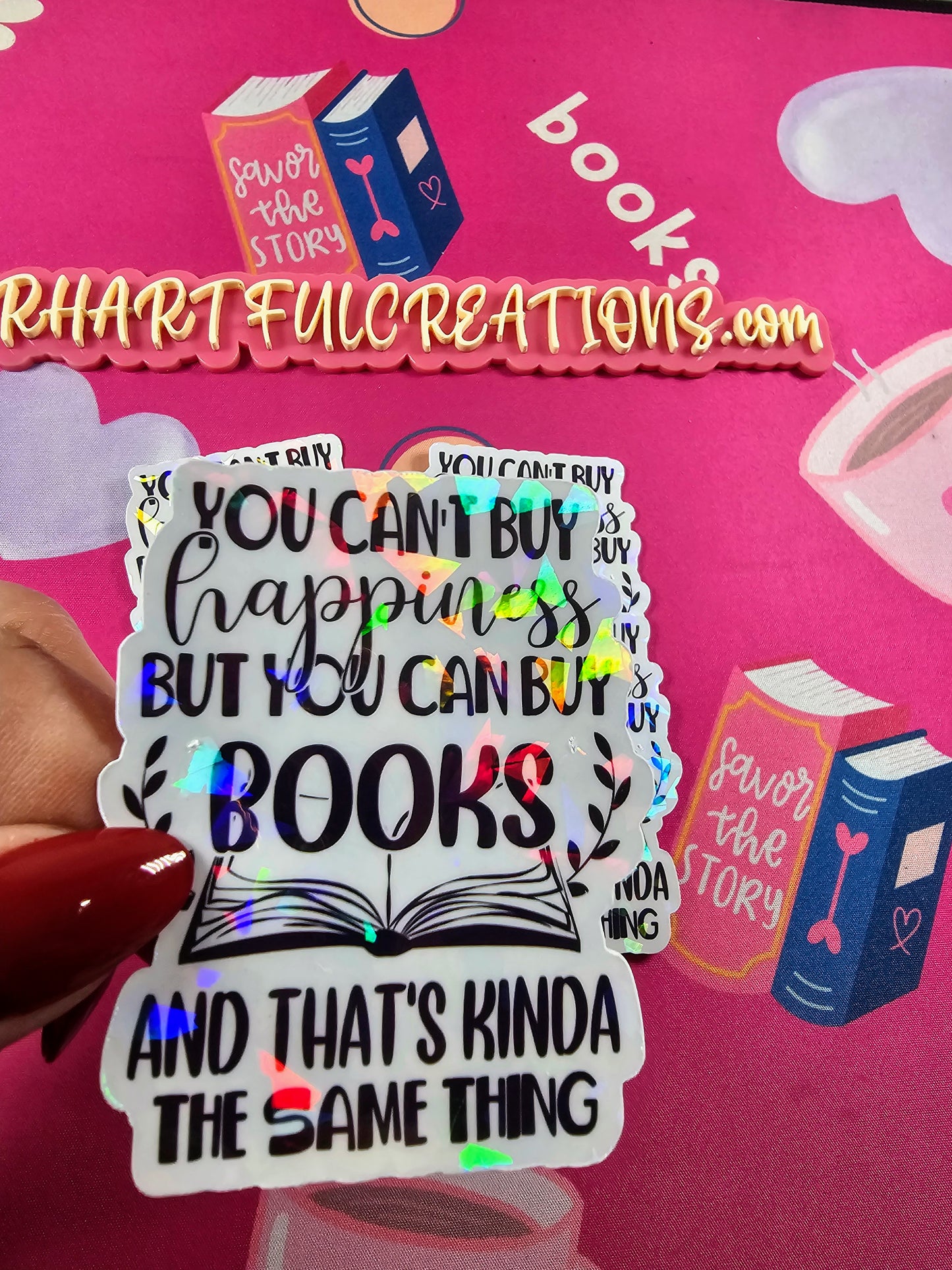 Sticker with book-themed text held over a pink background with 'Rhartful Creations' branding.