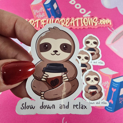 Cute handmade sloth sticker holding a coffee cup with the words “Slow down and relax”, cozy book lover  decal by RH Artful Creations.